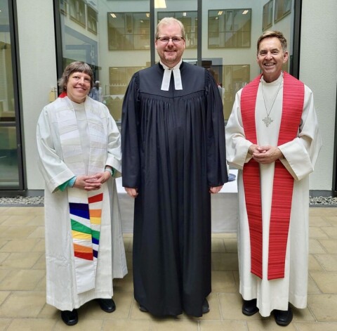 Pastorin Corinna Gehrke in weißer Albe mit bunter Stola, Pastor Paschen im Schwarzen Talar und Pastor Brinkmann mit weißer Albe und roter Stola